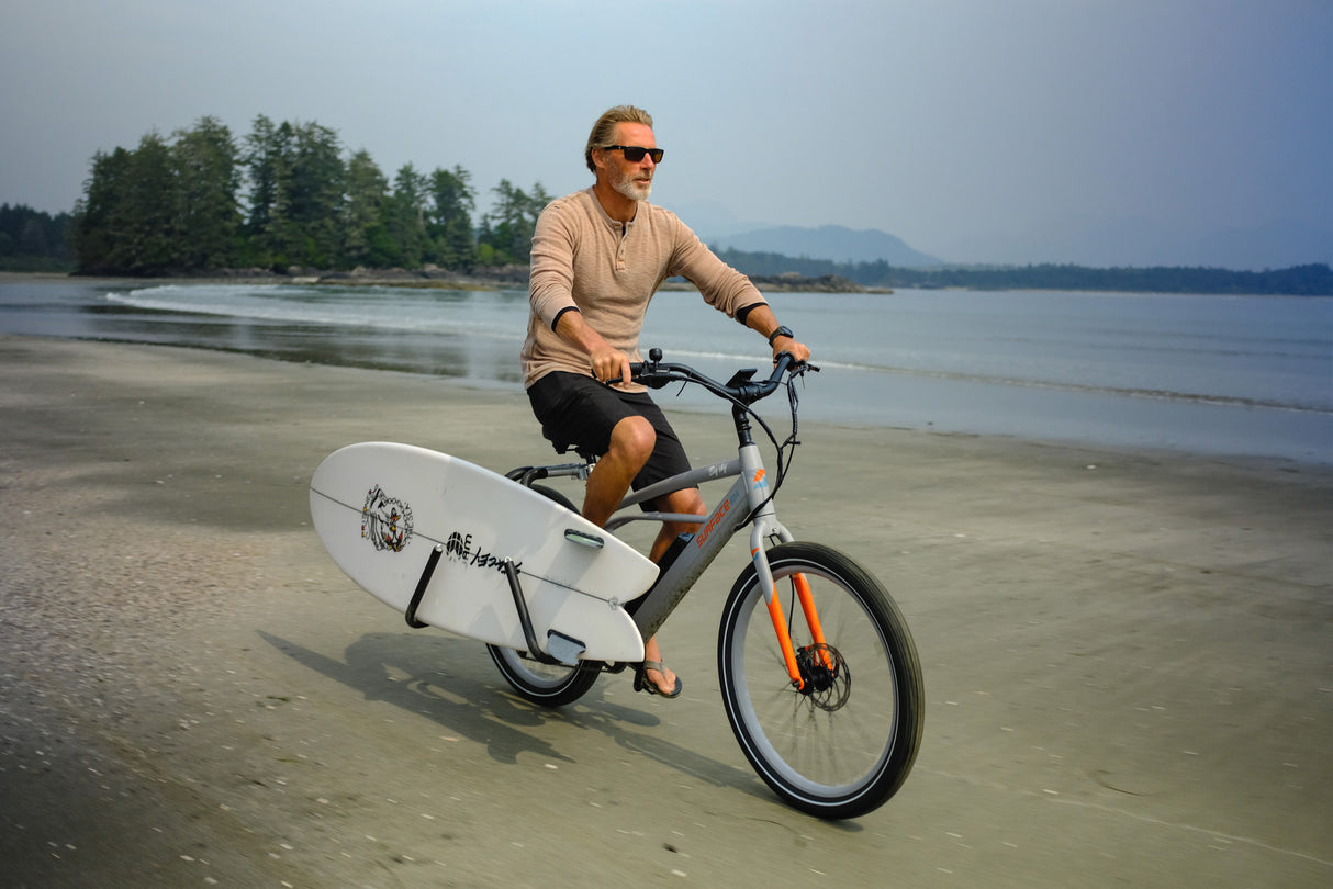 Man riding a Surface604 Big Sky on the beech with a surfboard